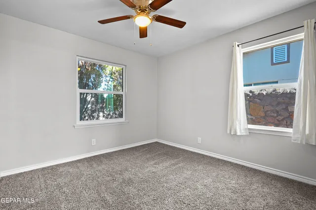 an empty room with windows and fan