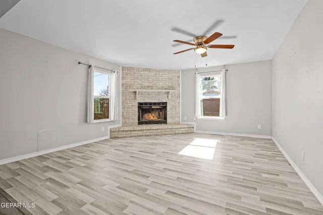 a view of a livingroom with a fireplace a ceiling fan and wooden floor