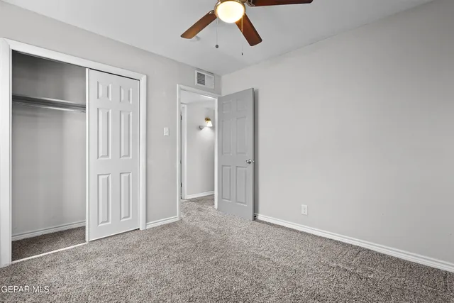 an empty room with a ceiling fan and carpet