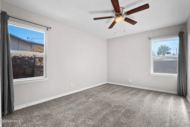 an empty room with windows and fan