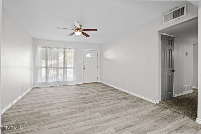 a view of empty room with wooden floor and fan