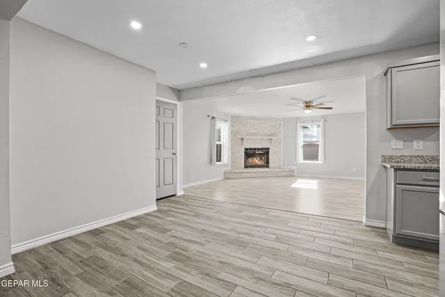a view of empty room with kitchen and fireplace