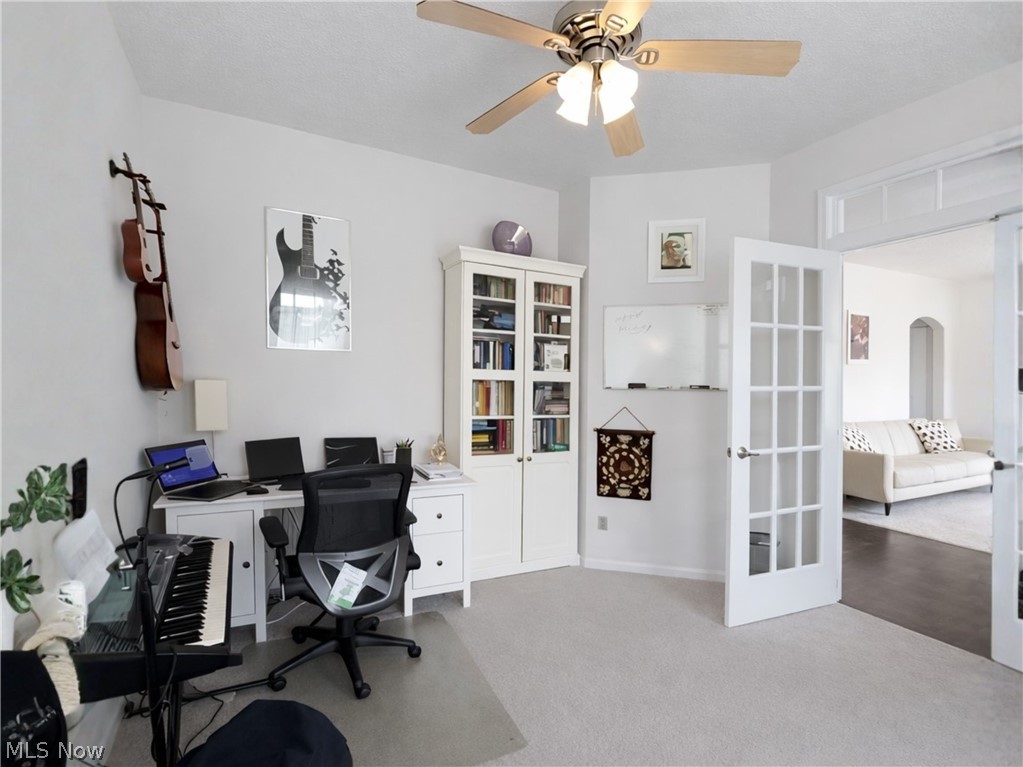 4509 Millbrook Way Akron, OH 44321 - Photo 5 of 27 Bright interior space featuring a ceiling fan with light fixture, light-colored carpeting, French doors with clear glass panes, and a built-in white cabinet with glass-fronted shelving