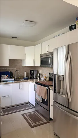 a kitchen with granite countertop a refrigerator and a stove top oven