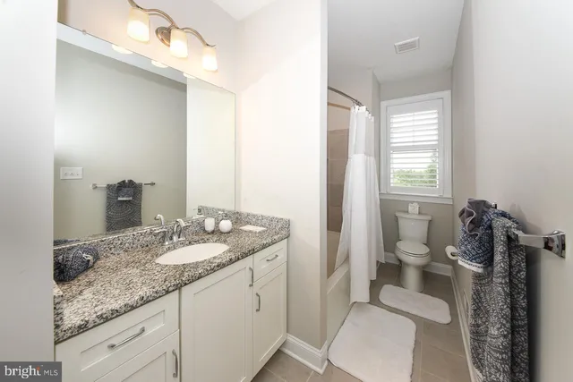 a bathroom with a granite countertop sink a toilet and a mirror