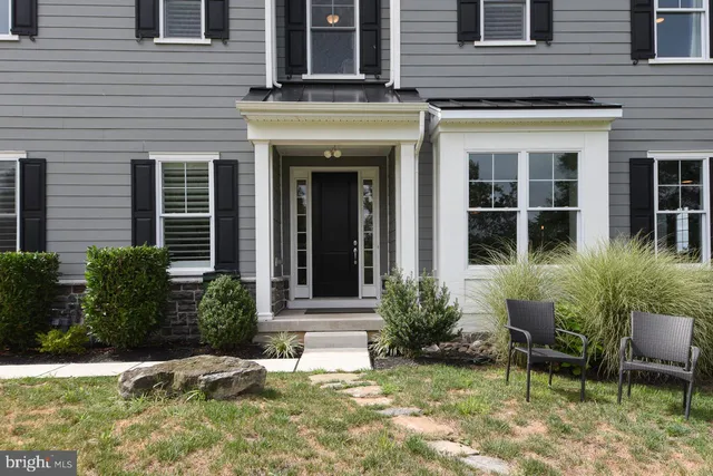 front view of a brick house with a yard chairs and table in a patio