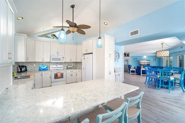 a kitchen with stainless steel appliances kitchen island granite countertop a dining table chairs and white cabinets