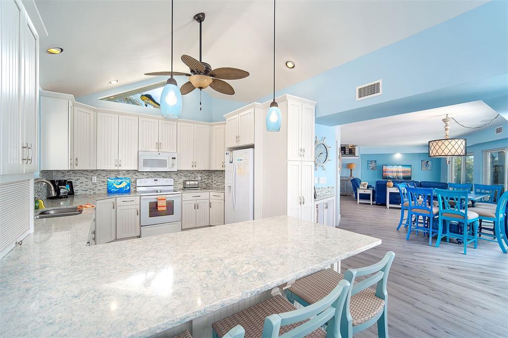 770 9th Street Key Colony Beach, FL 33051 - Photo 11 of 39 a kitchen with stainless steel appliances kitchen island granite countertop a dining table chairs and white cabinets