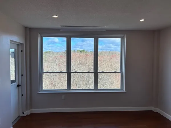 an empty room with wooden floor and windows