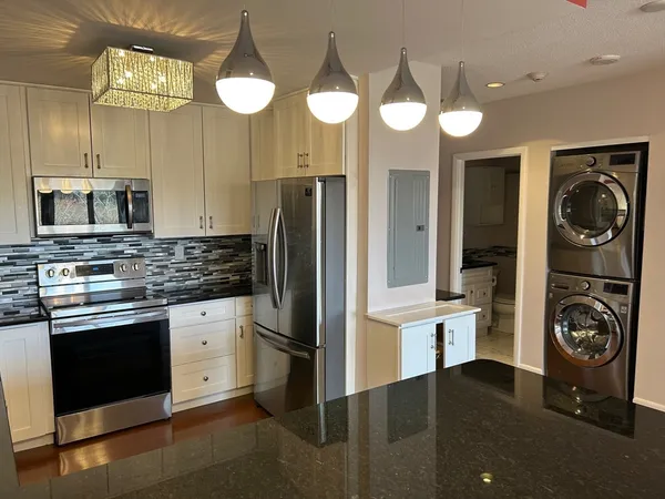 a kitchen with stainless steel appliances granite countertop a refrigerator and a stove top oven