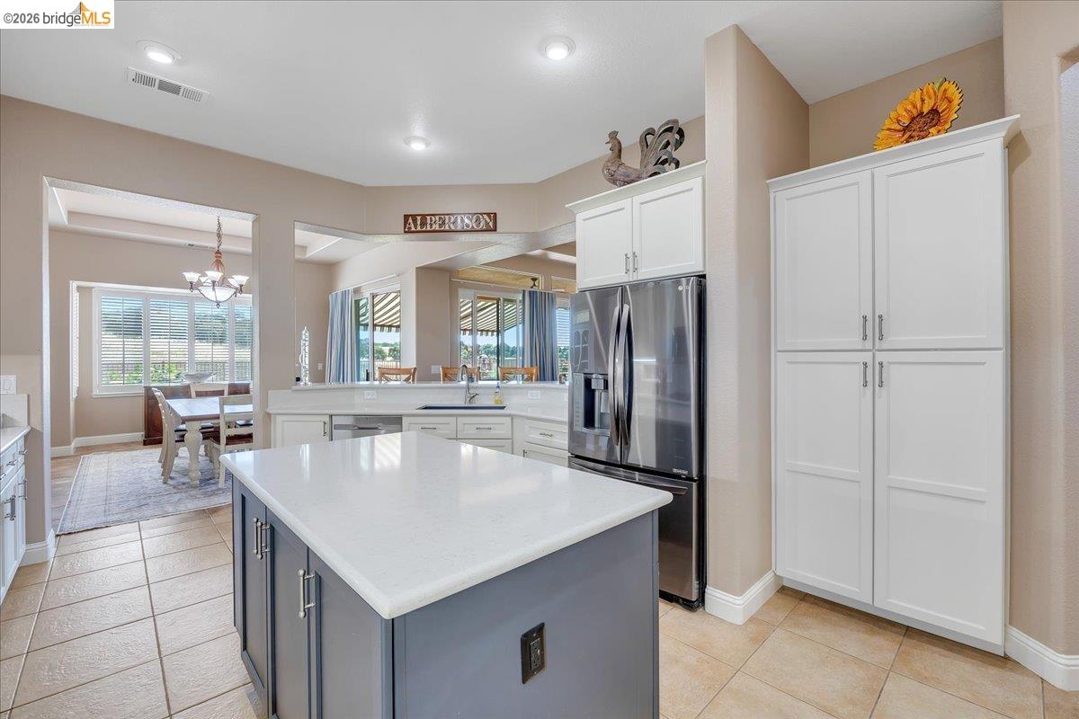 158 Rock Ridge Lane Copperopolis, CA 95228 - Photo 23 of 72 Kitchen featuring a contrasting island with a light-toned countertop, stainless steel refrigerator, white cabinetry, and recessed lighting
