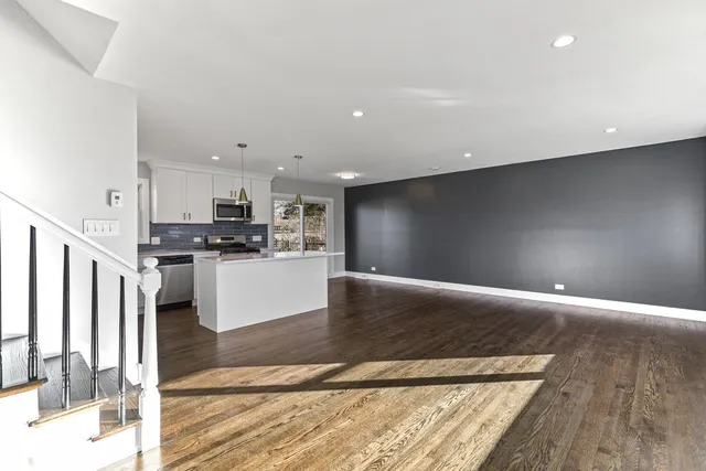 a kitchen with stainless steel appliances kitchen island granite countertop a refrigerator oven a sink with wooden cabinets and floors