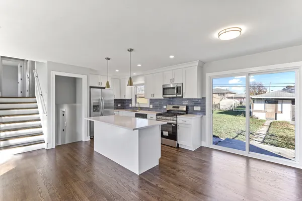 a kitchen with stainless steel appliances a refrigerator a stove top oven and white walls