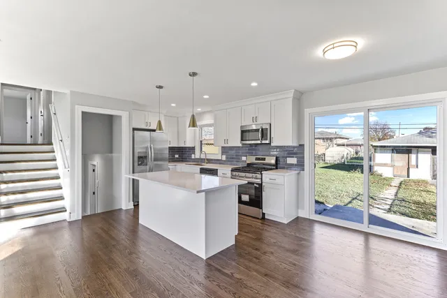 a kitchen with stainless steel appliances a refrigerator a stove top oven and white walls