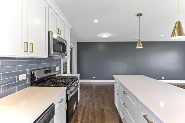 a kitchen that has a microwave a stove and white cabinets