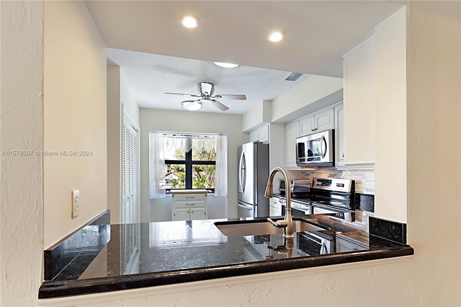 7864 Granada Place, Unit 504 Boca Raton, FL 33433 - Photo 17 of 65 a kitchen with kitchen island granite countertop a sink cabinets and stainless steel appliances