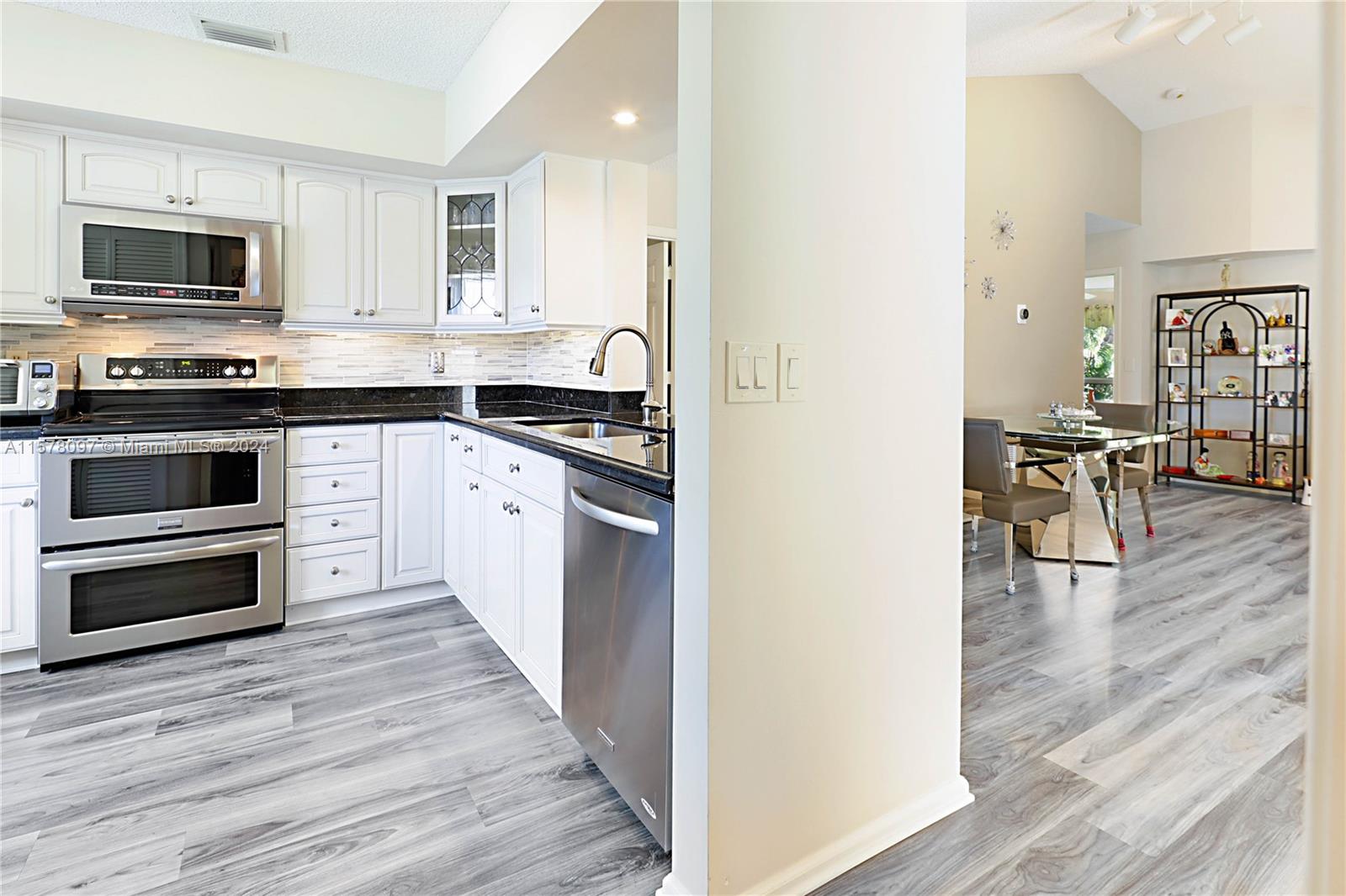 7864 Granada Place, Unit 504 Boca Raton, FL 33433 - Photo 20 of 65 a kitchen with granite countertop a stove top oven a sink dishwasher a dining table and chairs with wooden floor