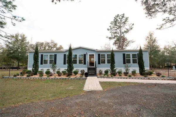 a front view of house with outdoor seating and covered with trees