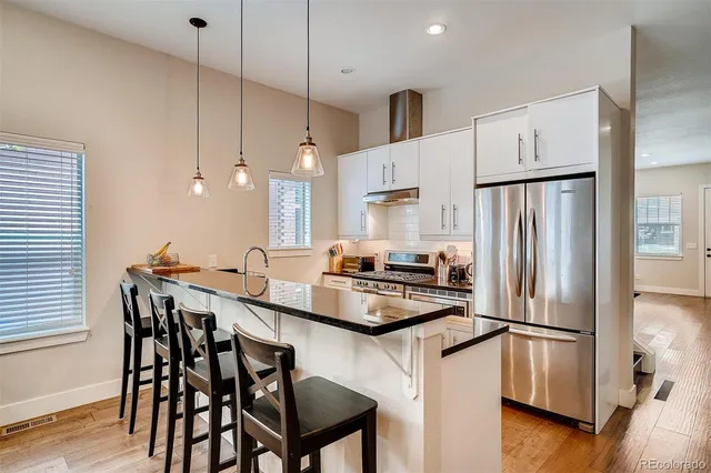 a kitchen with stainless steel appliances a refrigerator a stove a table and chairs