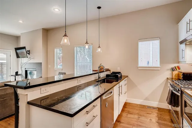 a kitchen with granite countertop a stove a sink and a refrigerator