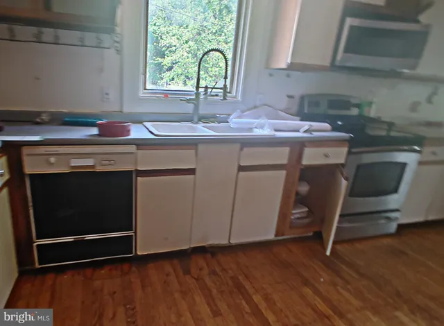 a kitchen with granite countertop a sink cabinets and wooden floor