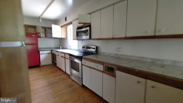 a kitchen with stainless steel appliances a sink a stove a microwave a sink a refrigerator and cabinets