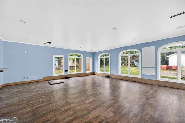 an empty room with wooden floor and windows