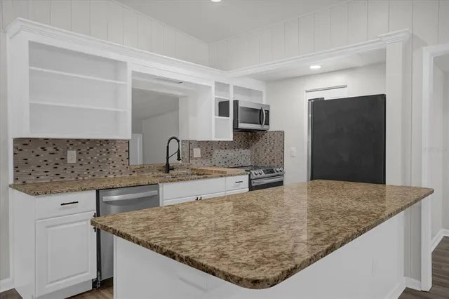 a kitchen with kitchen island granite countertop a sink and a refrigerator