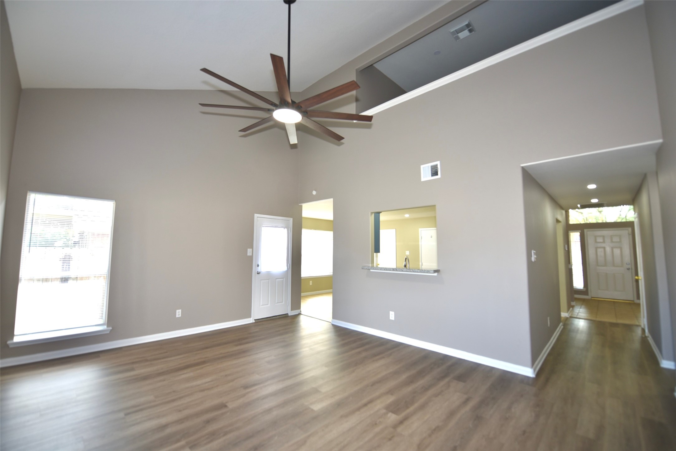 9611 Babbling Spring Court Tomball, TX 77375 - Photo 7 of 31 This room features high vaulted ceilings with a modern ceiling fan, wood flooring, and ample natural light. The open layout includes a pass-through to the kitchen and a hallway leading to the entrance.