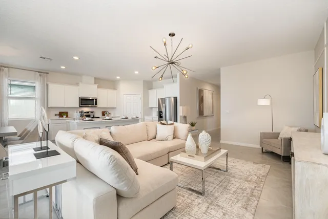 a living room with furniture kitchen view and a chandelier