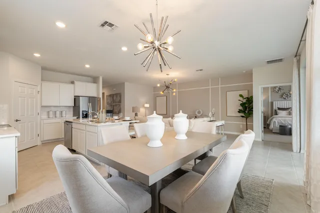 a dining room with kitchen island stainless steel appliances furniture a chandelier and kitchen view