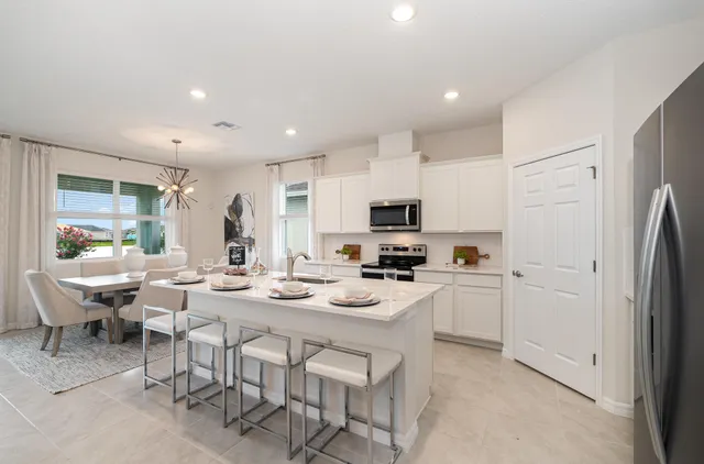 a kitchen with stainless steel appliances a stove a refrigerator a white table and chairs