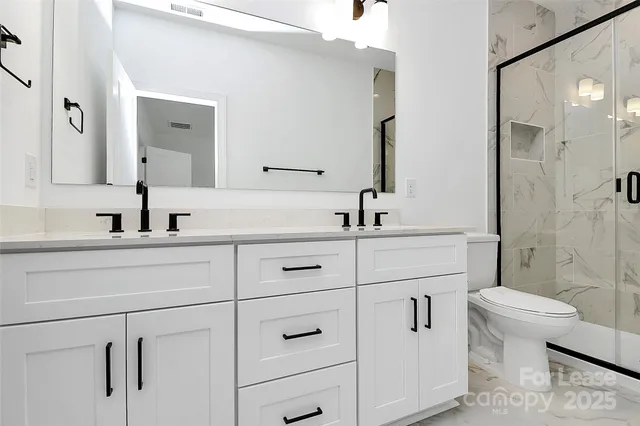 a bathroom with a double vanity sink toilet and shower