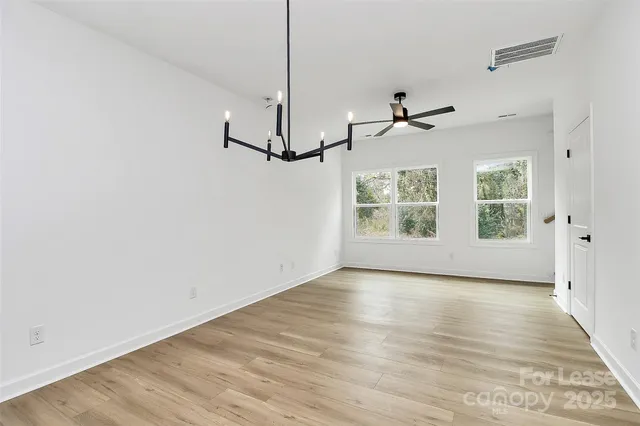a view of empty room with wooden floor and ceiling fan