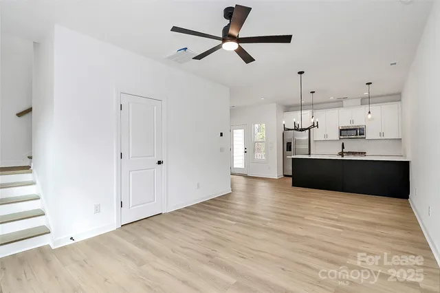 a view of kitchen and empty room with wooden floor