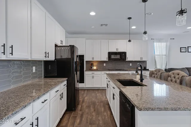 a kitchen with granite countertop a sink a counter top space stainless steel appliances and cabinets