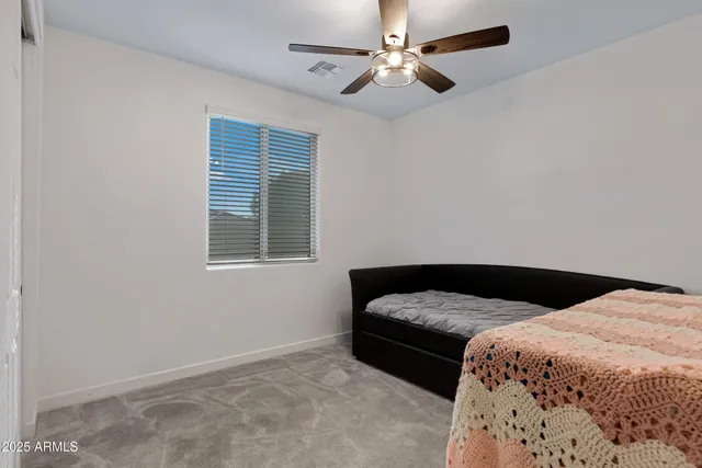 a bedroom with a bed ceiling fan and a window