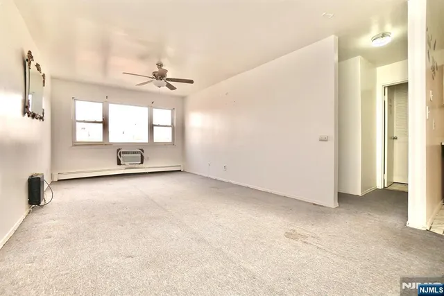 an empty room with windows and ceiling fan