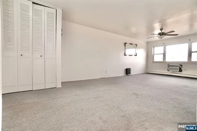 an empty room with windows and chandelier fan