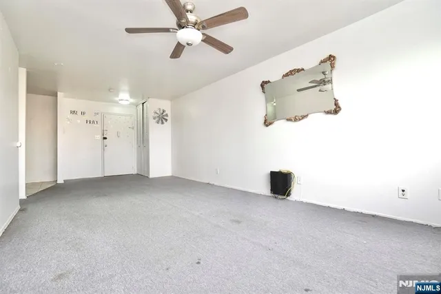 an empty room with ceiling fan and window
