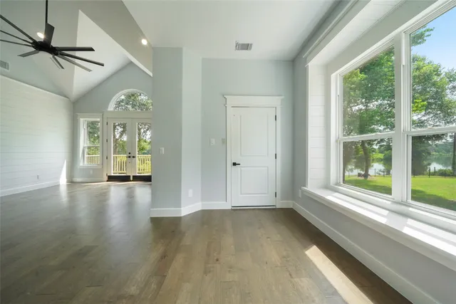a view of empty room with wooden floor and fan