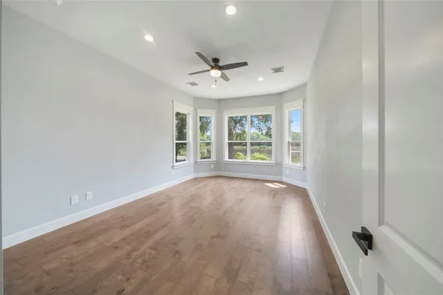 an empty room with wooden floor and windows