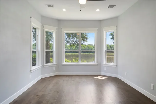 an empty room with wooden floor and windows