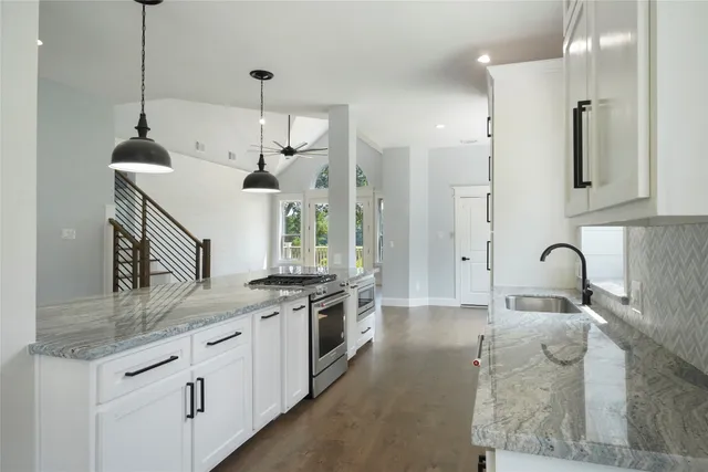 a kitchen with stainless steel appliances granite countertop a sink a stove and a refrigerator