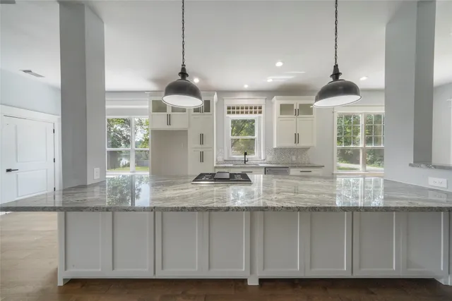 a kitchen with kitchen island granite countertop a large center island a sink stainless steel appliances and cabinets