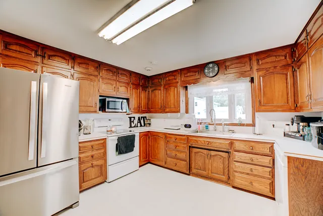 a kitchen with stainless steel appliances granite countertop a refrigerator a sink dishwasher a stove with cabinets and wooden floor