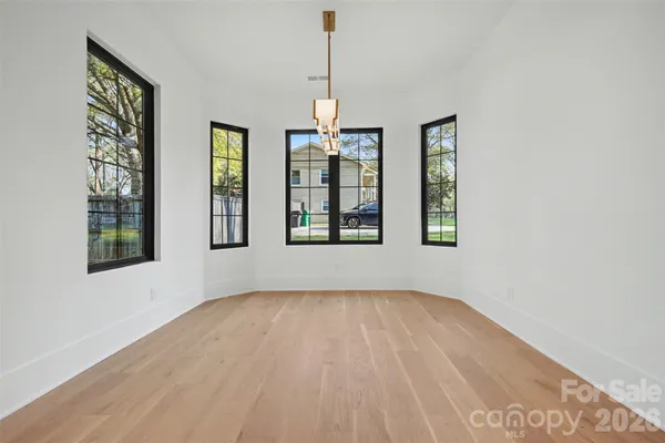 a view of an empty room with window and hardwood floor