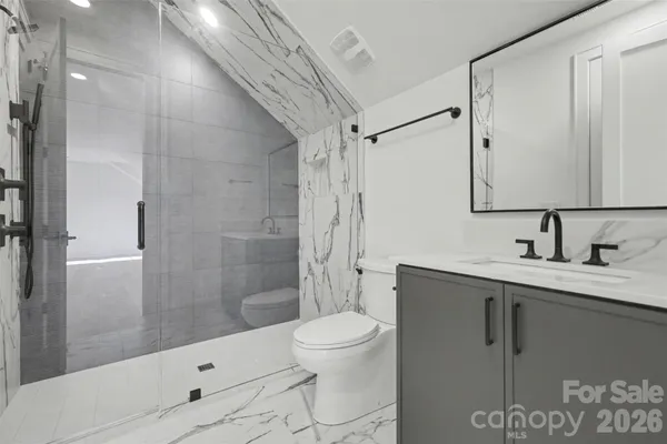 a bathroom with a granite countertop sink a toilet and shower