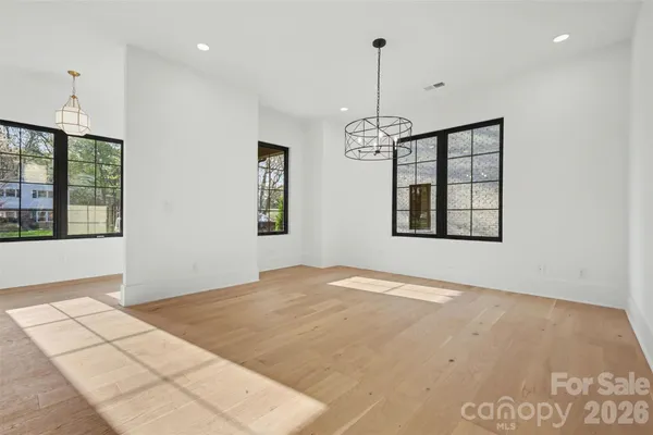 a view of an empty room with window and chandelier fan