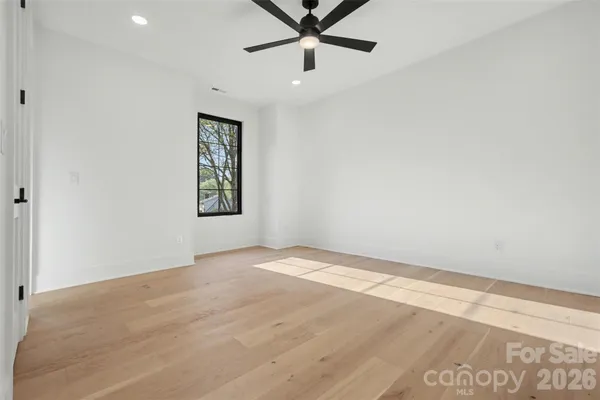 an empty room with a window and ceiling fan